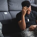 stressed african american soldier with army badge suffering from PTSD at home